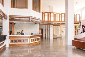 Eine großzügige Lobby mit einer Rezeption, einer Treppe und einer Sitzecke.