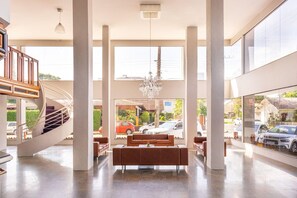 Eine geräumige Lobby mit einer zentralen Sitzgruppe, einer Wendeltreppe und großen Fenstern mit Blick auf die Straße.