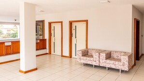 Ein geräumiger Flur mit einem blumigen Sofa, Holzschränken und Blick ins Freie.