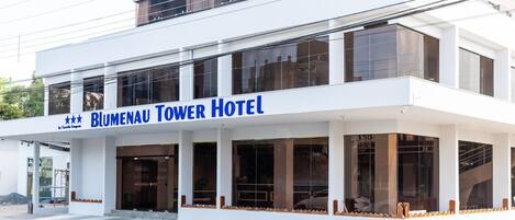 Um hotel moderno com uma placa de destaque que diz "Blumenau Tower Hotel".