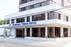 Um hotel moderno com uma placa de destaque que diz "Blumenau Tower Hotel".