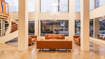 Un vestíbulo amplio con una zona de estar central, ventanas grandes y una escalera.