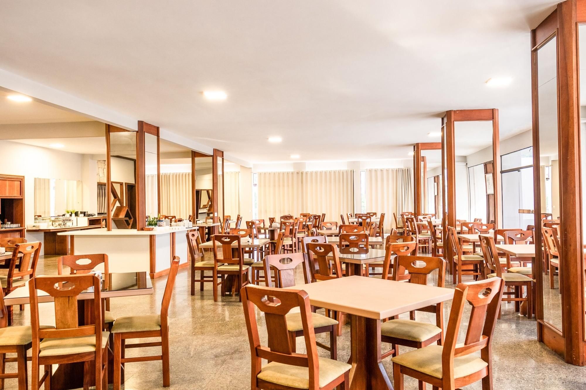 A spacious dining area with multiple tables and chairs, a counter with a display, and large mirrors on the walls.