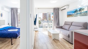 Una habitación de hotel moderna con cama, sofá y balcón con vista a edificios.