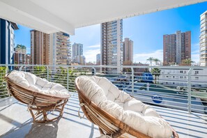 Un balcon avec des fauteuils en osier et une vue sur de hauts immeubles.