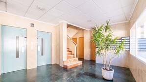Un vestíbulo con suelo de mármol, una escalera y una planta en maceta.