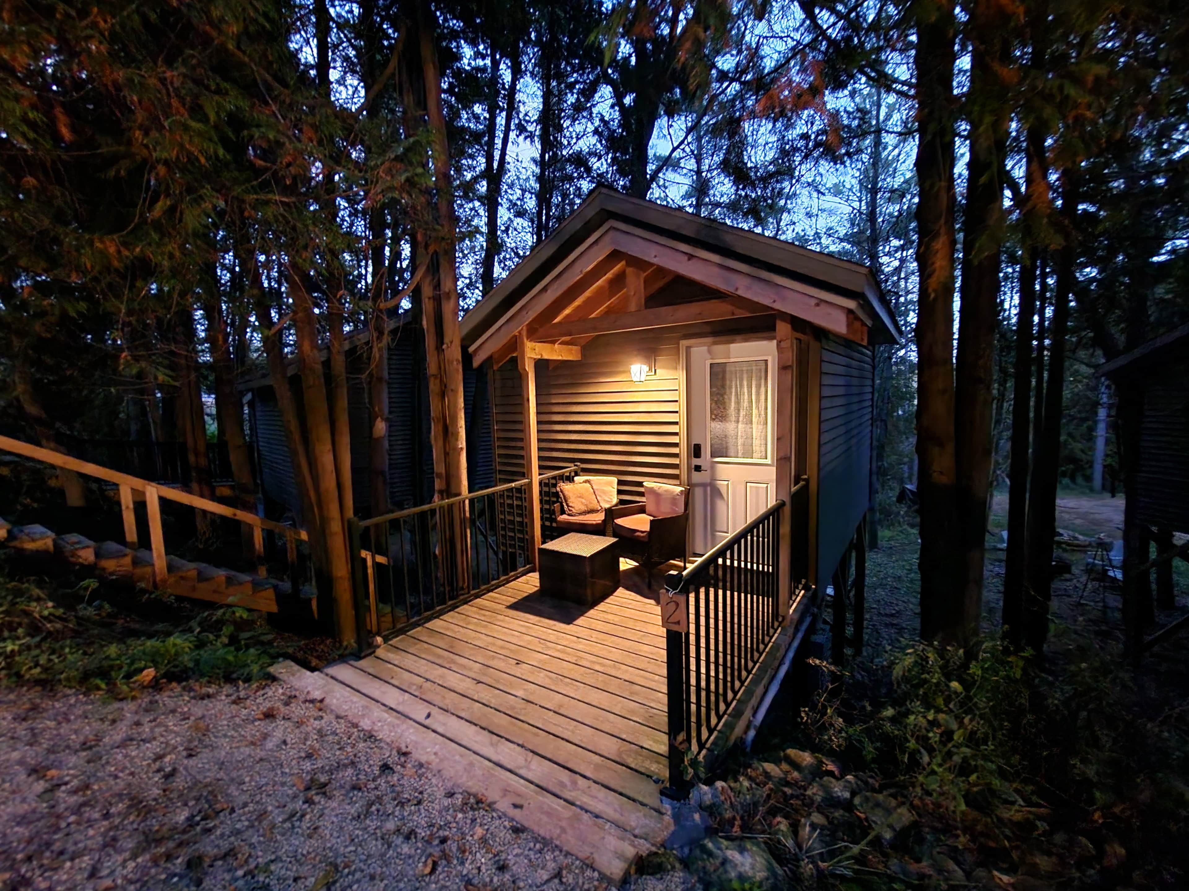 Une petite cabane avec une terrasse en bois, un canapé et une table.