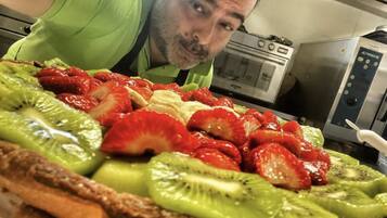 Una persona che si fa un selfie con una torta di frutta su un tavolo in cucina.