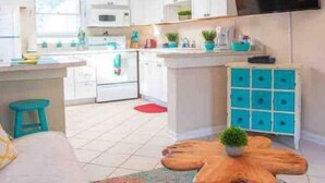 A modern kitchen with white cabinets, a central island, and a flat-screen TV mounted on the wall.