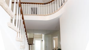 Eine Treppe mit weißen Geländern und Holzstufen, die zu einer Empore führt.