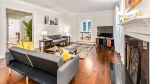 Ein modernes Wohnzimmer mit einem grauen Sofa, einem Fernseher und einem Kamin.