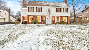 Ein zweigeschossiges Haus mit Ziegelverkleidung, einer Veranda und einem mit Schnee bedeckten Rasen.