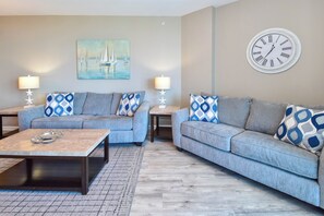 A living room with two sofas, a coffee table, and a wall clock.