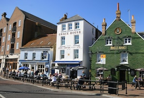 Eine Straße mit Gebäuden, darunter ein weißes Gebäude mit der Aufschrift 'Grace House' und ein grünes Gebäude mit der Beschilderung 'Poole Arms'.