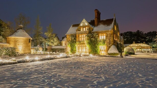 A large, illuminated building with a prominent tower and multiple windows, surrounded by a snow-covered landscape.