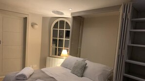 A bedroom with a bed, a window with a lamp, and a wardrobe.
