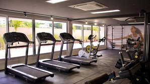Une salle de sport équipée de tapis de course, de vélos d’appartement et d’appareils de musculation.