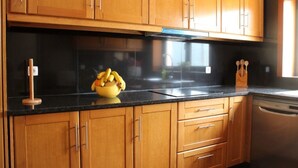 Cucina con mobili in legno, piano di lavoro nero e lavastoviglie.