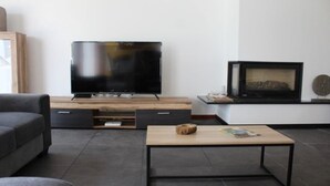 Un soggiorno moderno con televisore a schermo piatto, camino, divano e tavolino.