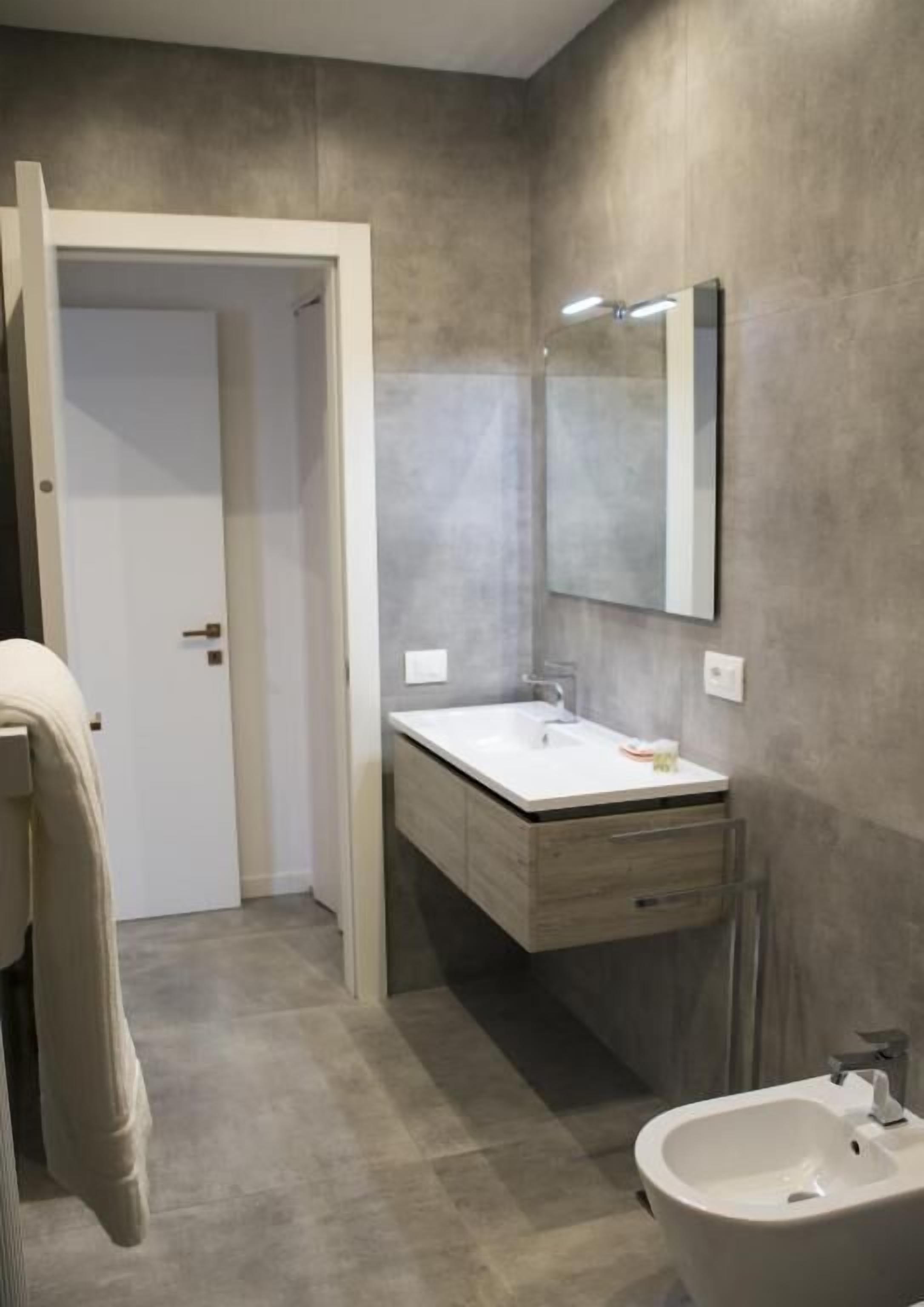 A modern bathroom with a white sink, a mirror, and a bathtub.