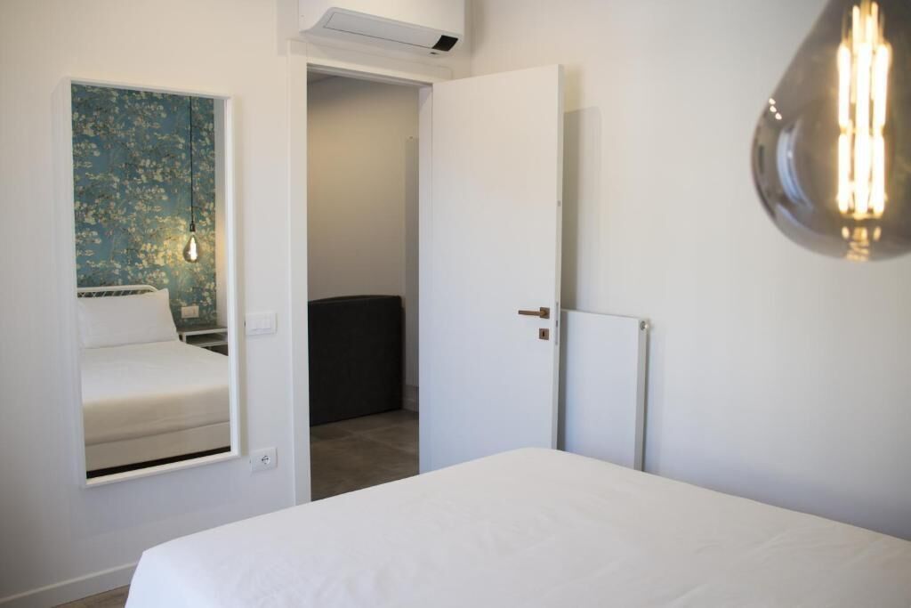 Ein Schlafzimmer mit einem Bett, einer Wandleuchte und einer Tür zu einem anderen Raum.