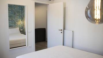 Ein Schlafzimmer mit einem Bett, einer Wandleuchte und einer Tür zu einem anderen Raum.