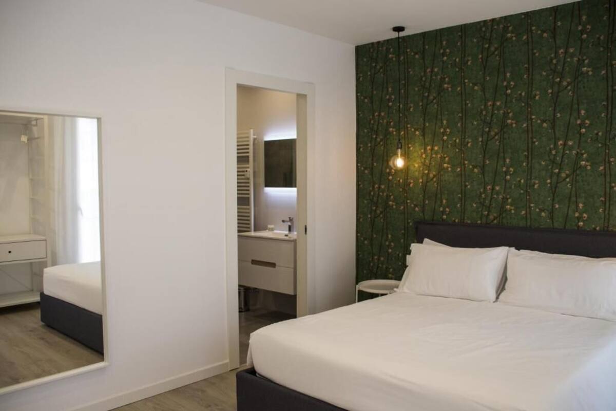 A bedroom with a bed, a mirror, a dresser, and a vanity.
