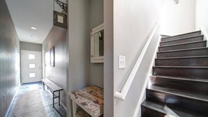 A hallway with a bench, a small table, and a staircase with dark wooden steps. - Modern 1-BR Condo—Stylish Stay Near Uptown CLT! (Charlotte)