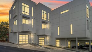 Ein modernes, mehrgeschossiges Wohngebäude mit mehreren Garagentoren und einer Auffahrt.