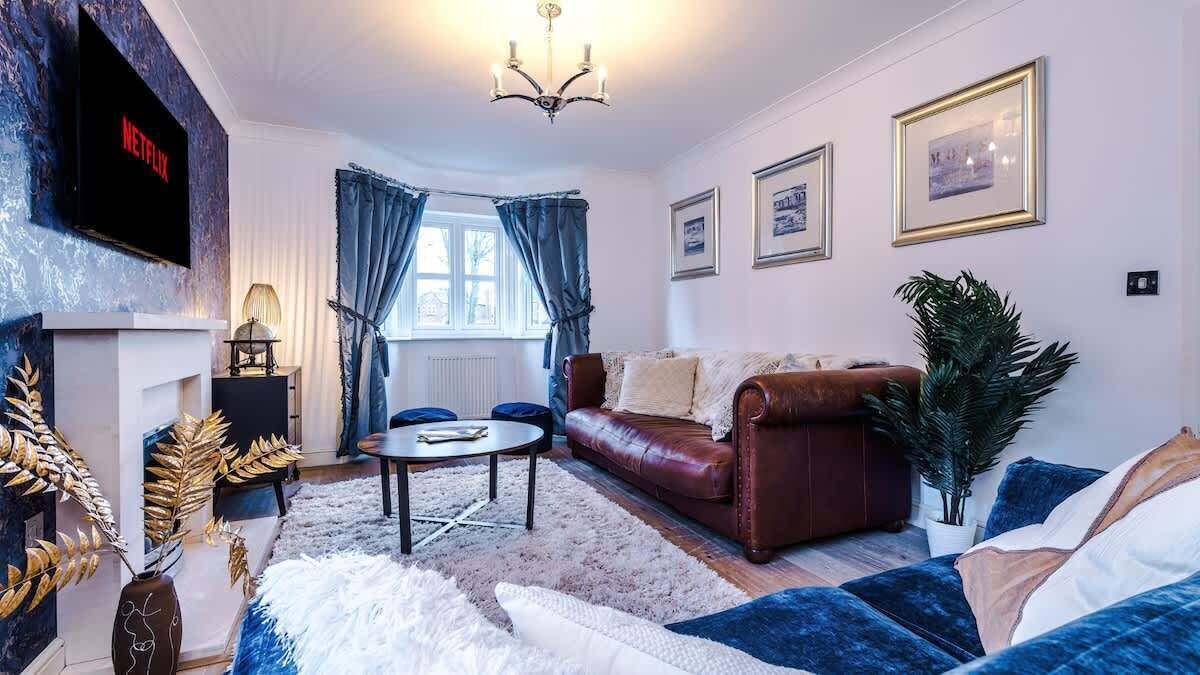 A living room with a fireplace, a leather sofa, a coffee table, and a TV mounted on the wall.