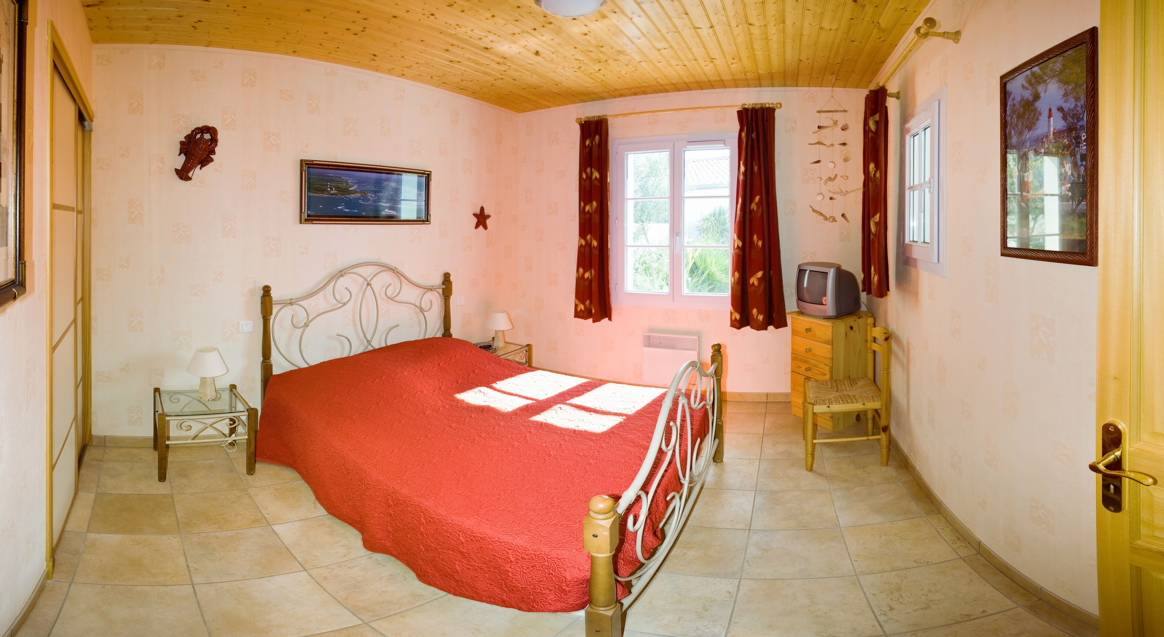 Een slaapkamer met een bed, nachtkastje, stoel, televisie en raam met gordijnen.
