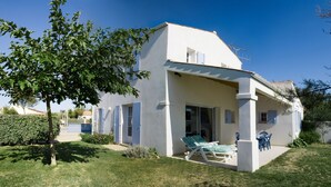 A two-story house with a patio area featuring a sun lounger and a table with chairs. - Maison 60 Mètres mer et Plage (Saint-Denis-d'Oléron)