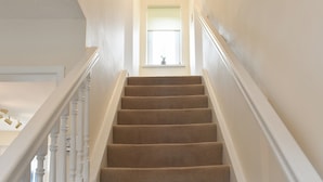 A staircase with carpeted steps, white railings, and a chandelier at the top. - 3 bedroom accommodation in Easington, near Staithes (Easington, near Staithes)
