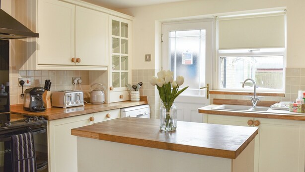 A kitchen with white cabinets, a wooden countertop, a coffee maker, a toaster, a kettle, and a vase with flowers. - 3 bedroom accommodation in Easington, near Staithes (Easington, near Staithes)