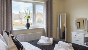A hotel room with a bed, a window with curtains, a radiator, a dresser, and a mirror. - 3 bedroom accommodation in Easington, near Staithes (Easington, near Staithes)