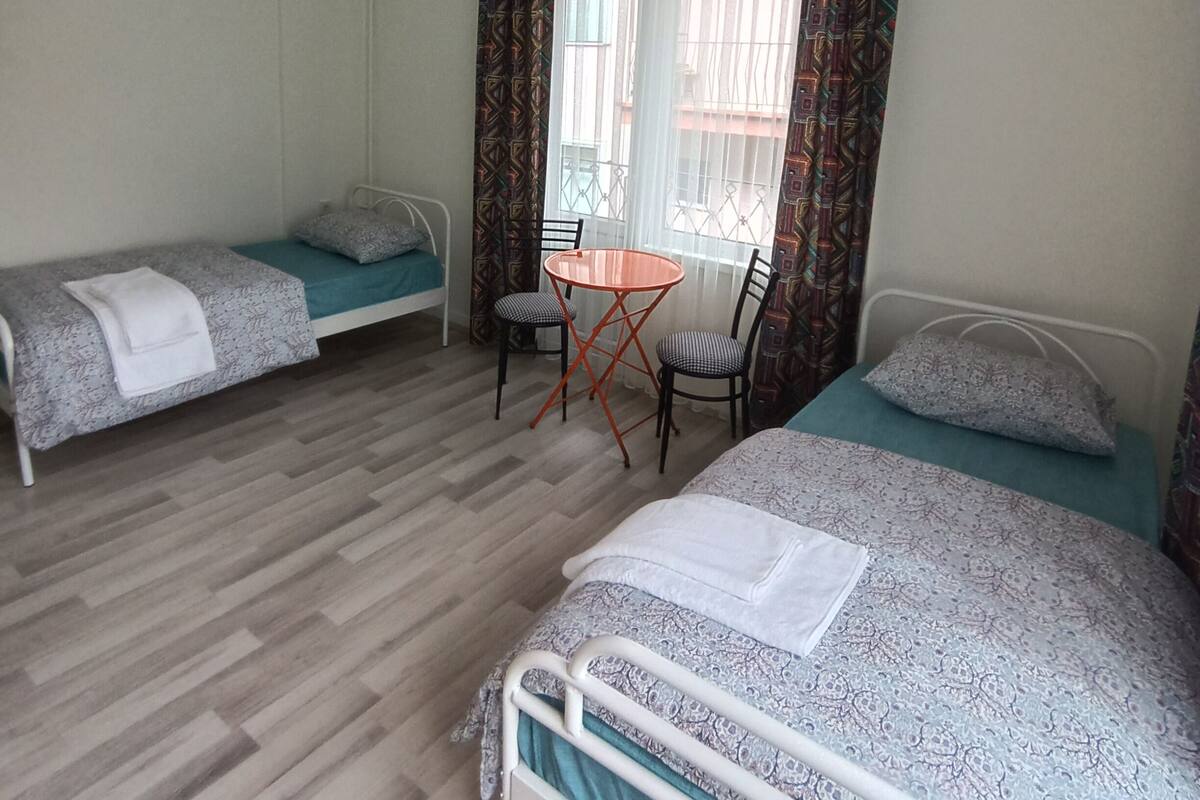 Un dormitorio con dos camas individuales, una mesita pequeña, sillas y una lámpara colgante.