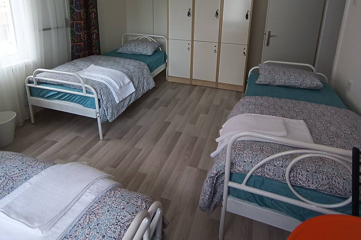 Una habitación con dos camas, un armario y una lámpara colgante.
