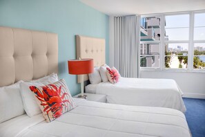 A hotel room with two beds, a red lamp, and a view of a cityscape through large windows.