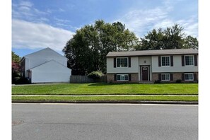 Stunning two-story home with a central entrance and attached garage, set amidst a beautifully manicured lawn.