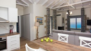 A modern kitchen with a wooden table, white cabinets, and a built-in oven. - Elsa Villa by Elrin Villas Mani (West Mani)