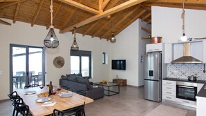 A modern kitchen with a stainless steel refrigerator, white cabinets, and a tiled backsplash. - Irini Villa by Elrin Villas Mani (West Mani)