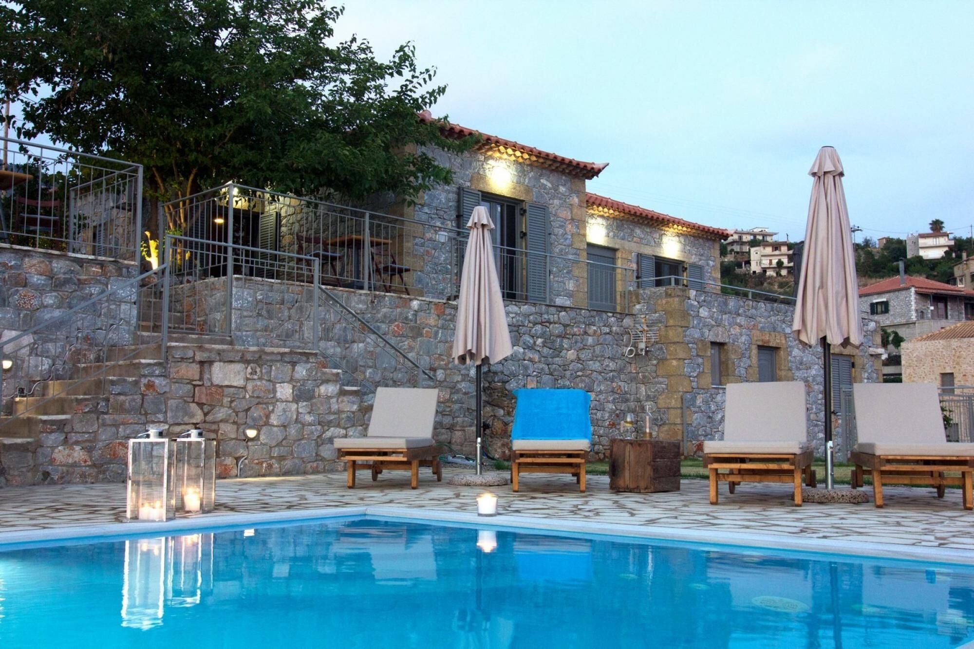 A pool area with stone walls, lounge chairs, and umbrellas.