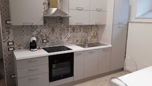 Una cucina moderna con lavastoviglie integrata, macchina da caffè e cappa aspirante in acciaio inox.