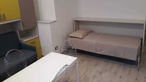 Una stanza compatta con un letto a castello, una piccola scrivania e una sedia.