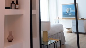 Een moderne slaapkamer met een bed, nachtkastje, lamp en een plank met decoratieve objecten.