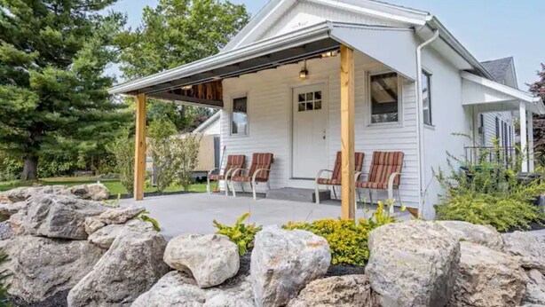 A white house with a covered porch and outdoor seating. - THE PEACEABLE NEST - Buffalo/Niagara Akron, NY (Newstead)