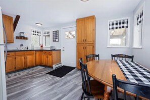 A kitchen with wooden cabinets, a dining table with chairs, and a checkered table runner.