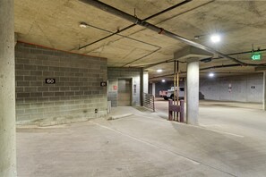 An underground parking garage with concrete walls, numbered parking spots, and an exit sign.