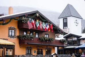 A building with a balcony decorated with flags, a clock tower, and a sign reading 'Hotel Gasthof.'