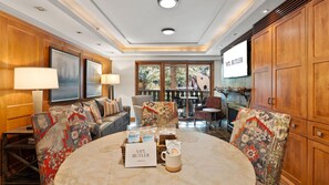 A well-lit room with a round table, sofas, and wooden cabinets. - Vail Village 1BR, 2BA condo for 4 with town views. (Vail)